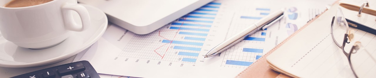 Charts, papers, glasses and a cup of coffee on the desk